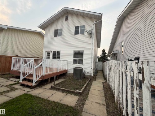 Rear exterior featuring white vinyl siding, a brown and white deck with white railings, and concrete paver walkway - 1535 80A Street Nw, Edmonton, AB - Outdoor With Deck Patio Veranda With Exterior