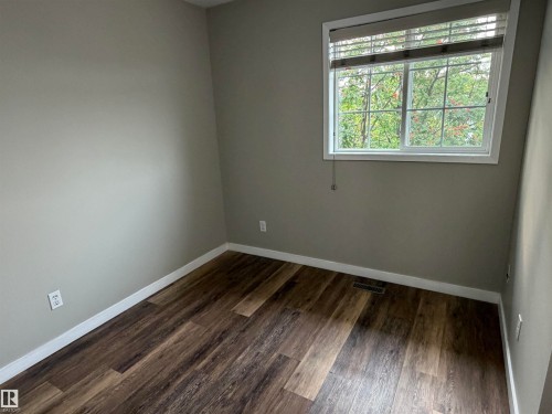 Wood-finish flooring, neutral wall tones, white trim, and a window with blinds - 1535 80A Street Nw, Edmonton, AB - Indoor Photo Showing Other Room