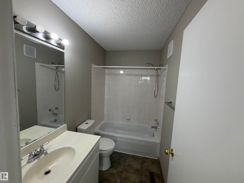 Bathroom featuring a vanity with integrated sink, chrome faucet, wall-mounted mirror, and a tub with shower - 1535 80A Street Nw, Edmonton, AB - Indoor Photo Showing Bathroom