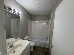 Bathroom featuring a vanity with integrated sink, chrome faucet, wall-mounted mirror, and a tub with shower - 