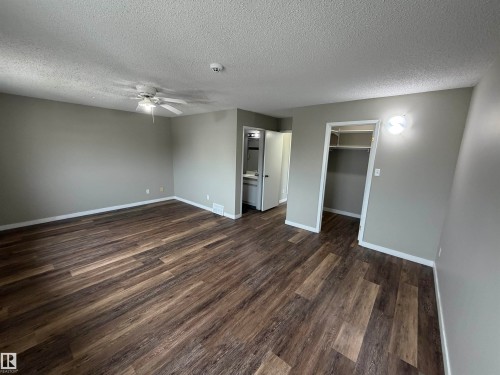 Spacious room with wood-finish flooring, neutral gray walls, and a ceiling fan - 1535 80A Street Nw, Edmonton, AB - Indoor Photo Showing Other Room