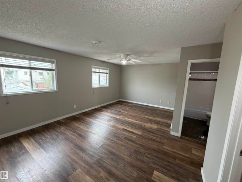 Spacious room featuring wood-finish flooring, neutral-toned walls, and multiple windows with blinds - 1535 80A Street Nw, Edmonton, AB - Indoor Photo Showing Other Room