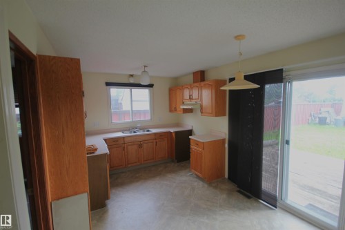 Kitchen featuring wood-finish cabinetry, a double basin sink, and laminate countertops - 16547 113 Street Nw, Edmonton, AB - Indoor Photo Showing Kitchen With Double Sink