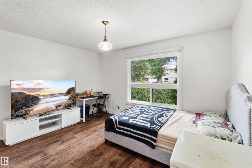 Wood-finish flooring, white walls, and a large window with white trim - 8723 81 Avenue Nw, Edmonton, AB - Indoor Photo Showing Bedroom