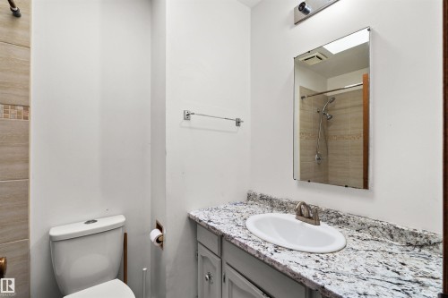 Vanity with a surface-mounted sink and brushed nickel faucet, set beneath a wall-mounted mirror - 8723 81 Avenue Nw, Edmonton, AB - Indoor Photo Showing Bathroom