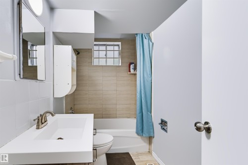 White vanity with integrated sink and brushed nickel faucet - 8723 81 Avenue Nw, Edmonton, AB - Indoor Photo Showing Bathroom