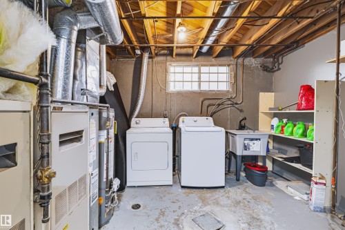 Utility space featuring exposed ceiling joists, a laundry sink, two appliances, and a window - 8723 81 Avenue Nw, Edmonton, AB - Indoor Photo Showing Laundry Room