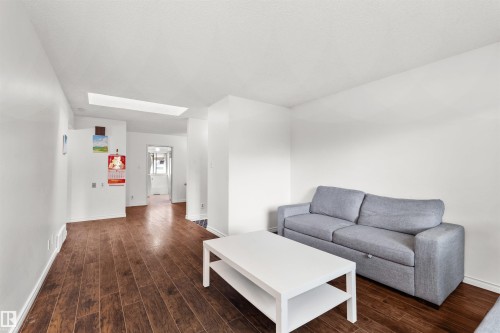 Wood-finish flooring, white walls, and a skylight - 8723 81 Avenue Nw, Edmonton, AB - Indoor Photo Showing Living Room