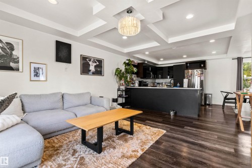 Recessed lighting, wood-finish flooring, tray ceilings, dark cabinetry, and stainless steel appliances - 15713 102 Avenue Nw, Edmonton, AB - Indoor Photo Showing Living Room