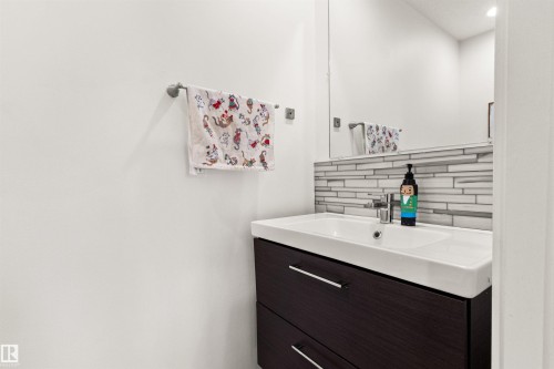 Vanity with an integrated rectangular sink, a dark wood-finish cabinet with drawer storage, and a linear tile backsplash - 15713 102 Avenue Nw, Edmonton, AB - Indoor Photo Showing Bathroom