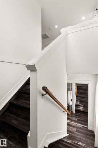 Dark wood-finish flooring with white trim, a wood handrail, and recessed lighting - 15713 102 Avenue Nw, Edmonton, AB - Indoor Photo Showing Other Room