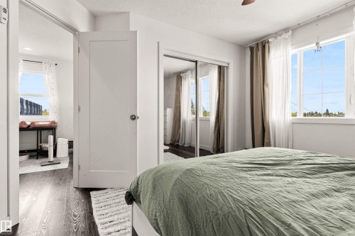 Wood-finish flooring throughout, white interior doors, and sliding mirrored closet doors - 15713 102 Avenue Nw, Edmonton, AB - Indoor Photo Showing Bedroom