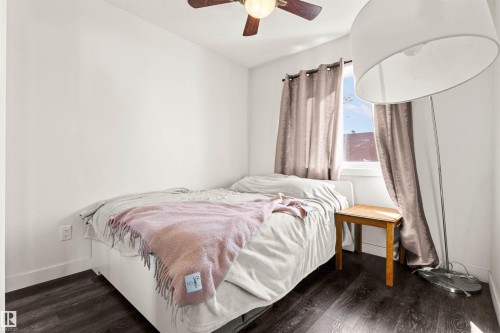 Dark wood-finish flooring, white painted walls, and a ceiling fan with integrated lighting - 15713 102 Avenue Nw, Edmonton, AB - Indoor Photo Showing Bedroom