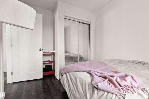 Dark wood-finish flooring, white walls, and a built-in closet with mirrored sliding doors - 15713 102 Avenue Nw, Edmonton, AB - Indoor Photo Showing Bedroom