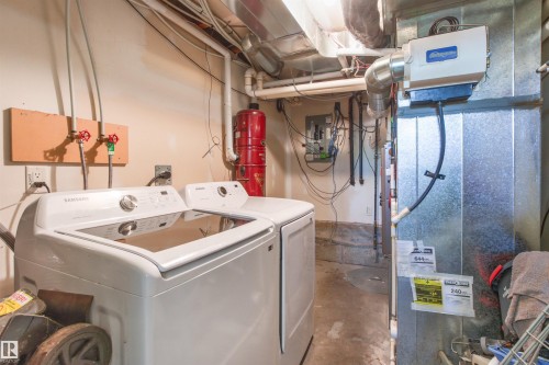Dedicated laundry area featuring a washer and dryer, adjacent to utility systems including a water heater and furnace with an attached humidifier - 15713 102 Avenue Nw, Edmonton, AB - Indoor Photo Showing Laundry Room
