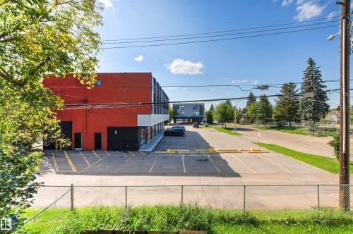 Red-painted commercial exterior with a black lower facade, featuring an adjacent asphalt parking area with yellow-painted markings - 15713 102 Avenue Nw, Edmonton, AB - Outdoor