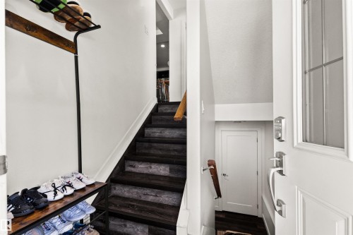 Entryway featuring a white paneled door with window insert, dark wood-finish stairs, and a white interior wall - 15713 102 Avenue Nw, Edmonton, AB - Indoor Photo Showing Other Room