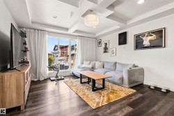 Expansive window offering abundant natural light, tray ceiling with recessed lighting, wood-finish flooring throughout, and a contemporary chandelier fixture - 