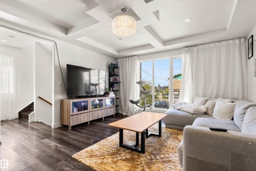 Coffered ceilings with recessed lighting, large picture windows, wood-finish flooring, and a contemporary chandelier - 15713 102 Avenue Nw, Edmonton, AB - Indoor Photo Showing Living Room