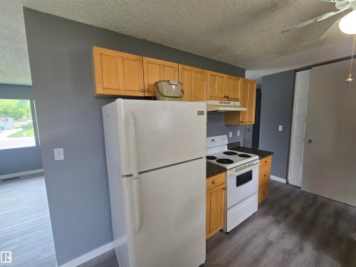Kitchen featuring wood cabinetry, white appliances, and laminate flooring - 10829 167A Avenue Nw, Edmonton, AB - Indoor Photo Showing Kitchen