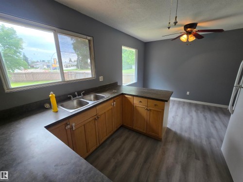 U-shaped kitchen counter with a double basin sink, natural wood-finish cabinetry, and wood-finish flooring - 10829 167A Avenue Nw, Edmonton, AB - Indoor Photo Showing Kitchen With Double Sink