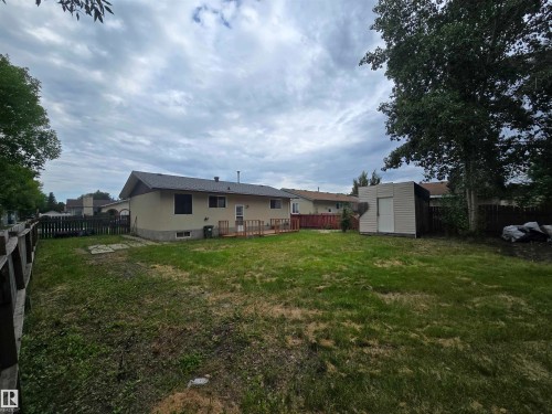 Expansive backyard with a wooden fence, featuring a deck, a storage shed, and mature trees - 10829 167A Avenue Nw, Edmonton, AB - Outdoor With Backyard