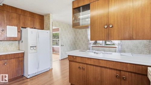 Wood-finish cabinetry with white countertops, wood-finish flooring, and a white side-by-side refrigerator - 52012 Hwy 21, Rural Strathcona County, AB - Indoor Photo Showing Kitchen