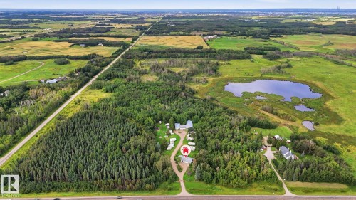 Expansive property featuring dense wooded areas, open green fields, a substantial pond, and paved road frontage - 52012 Hwy 21, Rural Strathcona County, AB - Outdoor With View