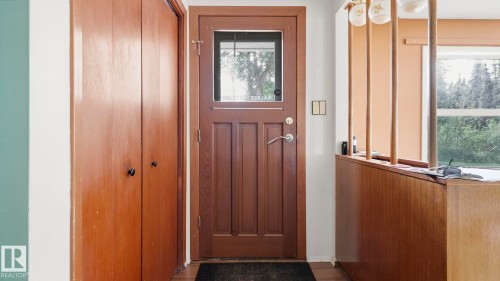 Wood-paneled door with a transom window, bi-fold closet doors, and wood-finish flooring - 52012 Hwy 21, Rural Strathcona County, AB - Indoor Photo Showing Other Room