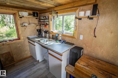 Compact kitchen space featuring wood-finish wall panels, a double basin sink, and white base cabinetry - 347, 58532 Range Rd 113, Rural St. Paul County, AB 