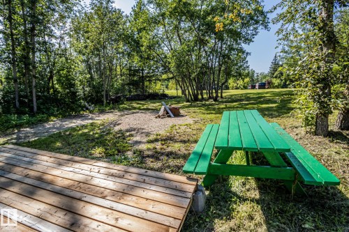Expansive outdoor area featuring a wood-plank deck, gravel fire pit, and mature trees - 347, 58532 Range Rd 113, Rural St. Paul County, AB 