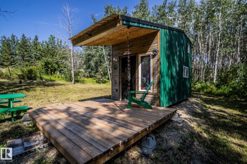 Wood-sided structure with green accent paneling, featuring an attached wood deck and covered entry - 347, 58532 Range Rd 113, Rural St. Paul County, AB 