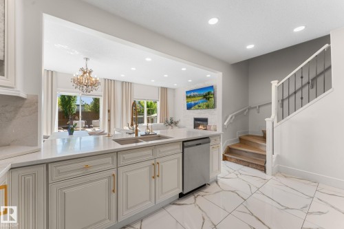 Kitchen island featuring an undermount sink, brass-finish faucet, and integrated dishwasher - 5415 167A Avenue Nw, Edmonton, AB - Indoor Photo Showing Kitchen With Double Sink