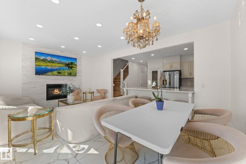 Recessed lighting and a decorative chandelier illuminate the space, featuring a fireplace with a stone-clad surround - 5415 167A Avenue Nw, Edmonton, AB - Indoor Photo Showing Other Room With Fireplace