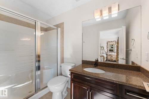 Shower enclosure with frosted glass panels, dark wood-finish vanity with an integrated sink, brown speckled countertop, and a contemporary vanity light fixture - 5415 167A Avenue Nw, Edmonton, AB - Indoor Photo Showing Bathroom