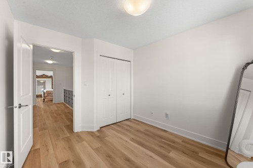 Neutral color palette, wood-finish flooring, white trim, and bi-fold closet doors - 5415 167A Avenue Nw, Edmonton, AB - Indoor Photo Showing Other Room