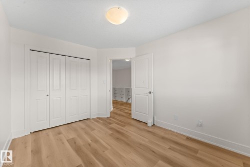 Wood-finish flooring, white walls, bi-fold closet doors, and flush-mount ceiling lighting - 5415 167A Avenue Nw, Edmonton, AB - Indoor Photo Showing Other Room