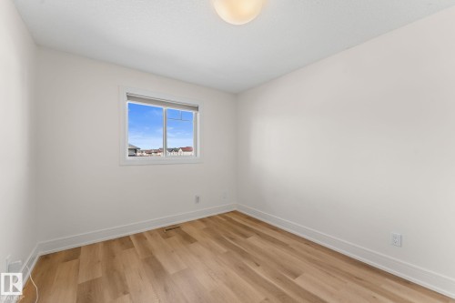 Neutral wall finishes, wood-finish flooring, and a single window with blinds - 5415 167A Avenue Nw, Edmonton, AB - Indoor Photo Showing Other Room