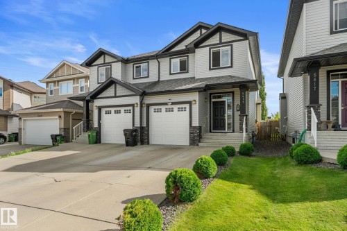 Two-story duplex with light grey siding, black trim, and a prominent front-facing garage - 5415 167A Avenue Nw, Edmonton, AB - Outdoor With Facade