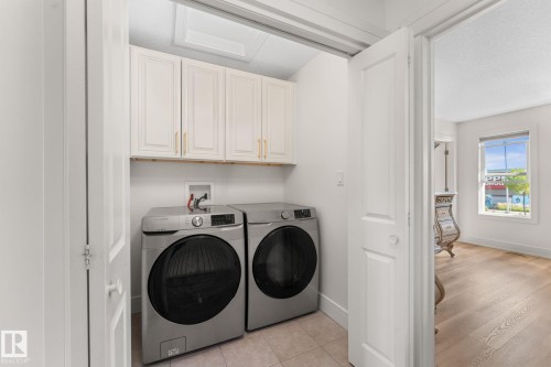 Laundry area featuring upper cabinetry with gold-tone hardware and neutral tile flooring - 5415 167A Avenue Nw, Edmonton, AB - Indoor Photo Showing Laundry Room