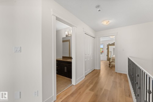 Wood-finish flooring throughout, white walls, and a built-in closet with bi-fold doors - 5415 167A Avenue Nw, Edmonton, AB - Indoor Photo Showing Other Room