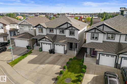 Townhome exteriors featuring light-colored siding, dark trim accents, and attached garages - 5415 167A Avenue Nw, Edmonton, AB - Outdoor With Facade