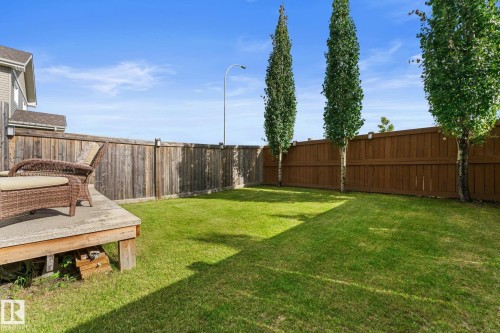 Expansive backyard featuring a concrete patio, lush green lawn, full privacy fencing, and mature trees - 5415 167A Avenue Nw, Edmonton, AB - Outdoor