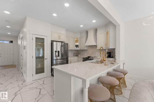 Kitchen featuring white cabinetry, light-toned countertops, a gold-toned faucet, stainless steel appliances, and recessed lighting - 5415 167A Avenue Nw, Edmonton, AB - Indoor Photo Showing Kitchen