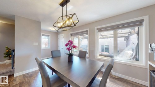 Dining area featuring a geometric chandelier, wood-finish flooring, and multiple windows - 17359 49 Street Nw, Edmonton, AB - Indoor Photo Showing Dining Room