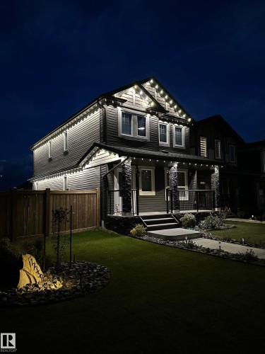 Two-story residence with a covered front porch featuring stone-clad columns and black railings - 17359 49 Street Nw, Edmonton, AB - Outdoor With Deck Patio Veranda With Facade