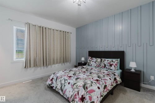 Accent wall with vertical paneling, light gray carpeting, and a window with blinds - 104 Meadowview Way, Leduc, AB - Indoor Photo Showing Bedroom