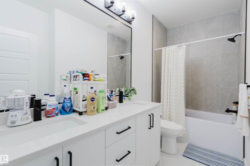 White dual vanity with integrated sinks, black hardware, and a large mirror - 104 Meadowview Way, Leduc, AB - Indoor Photo Showing Bathroom