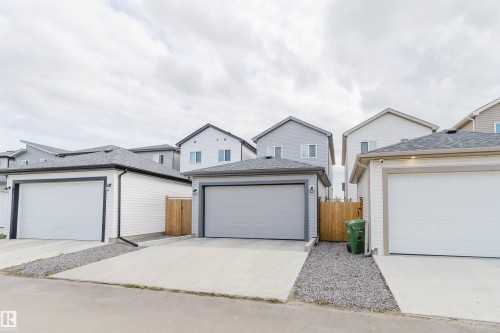Detached garage with white overhead door, concrete driveway, and gravel landscaping - 104 Meadowview Way, Leduc, AB - Outdoor