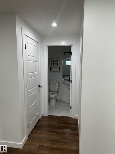 Hallway featuring wood-finish flooring, recessed lighting, and a white paneled door with black hardware - 104 Meadowview Way, Leduc, AB - Indoor Photo Showing Other Room